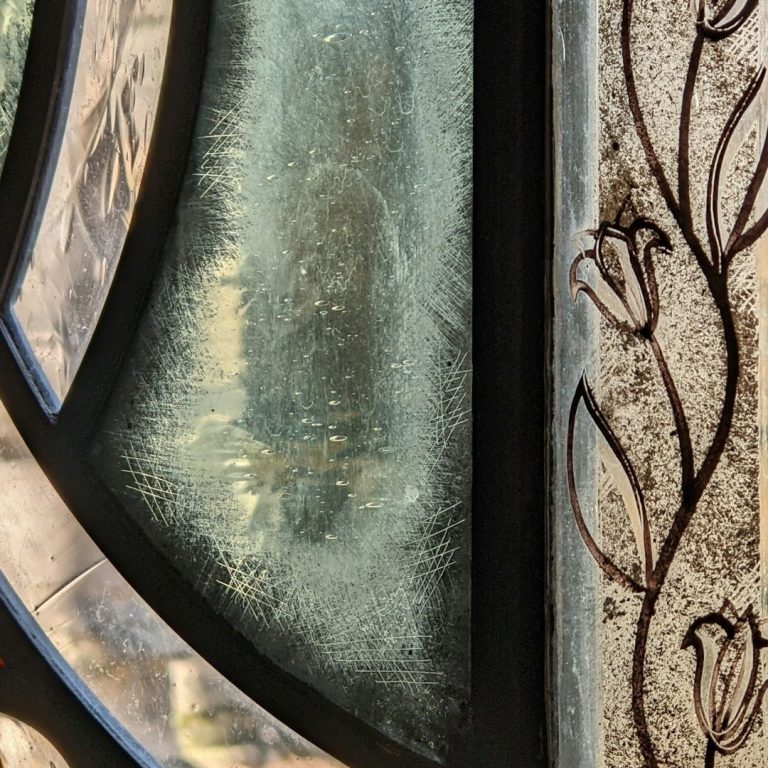 Buntes Glasfenster mit floralem Muster und zentralem rot-gelbem Stern.