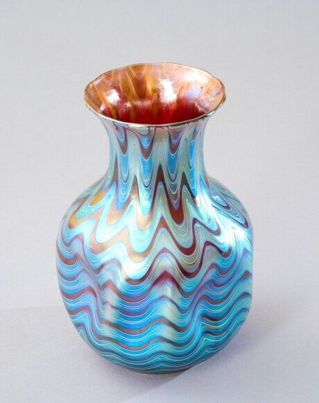 Bunt gemusterte, schmalhalsige Vase mit wellenförmigen Designs in Blau und Kupfer.