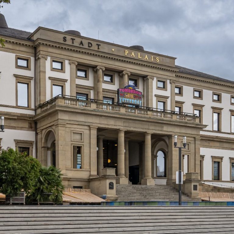 StadtPalais - Museum für Stuttgart Historisches Gebäude mit Säulen, Eingangsbereich und Wolken am Himmel.