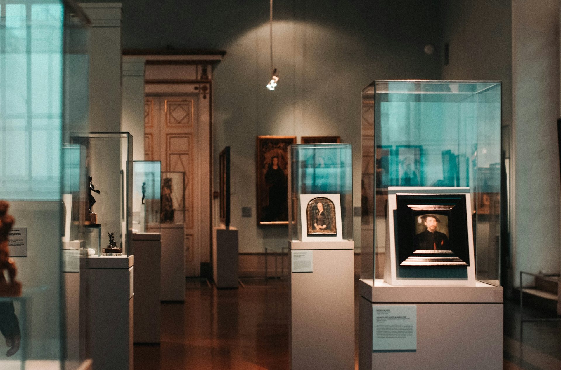 Innenansicht eines Museums mit Skulpturen und Gemälden in Glasvitrinen.