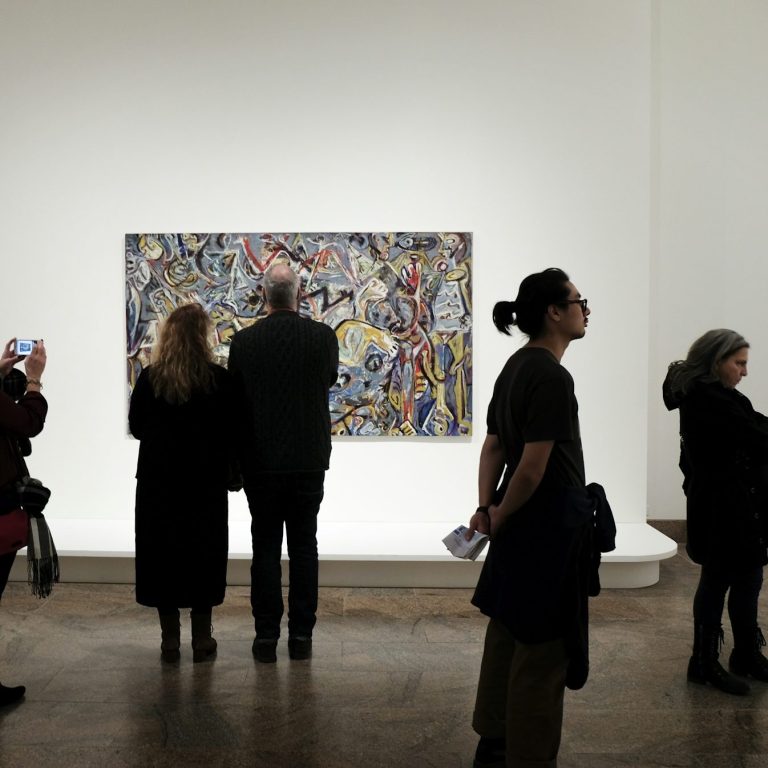 Besucher betrachten ein abstraktes Gemälde in einer Galerie.